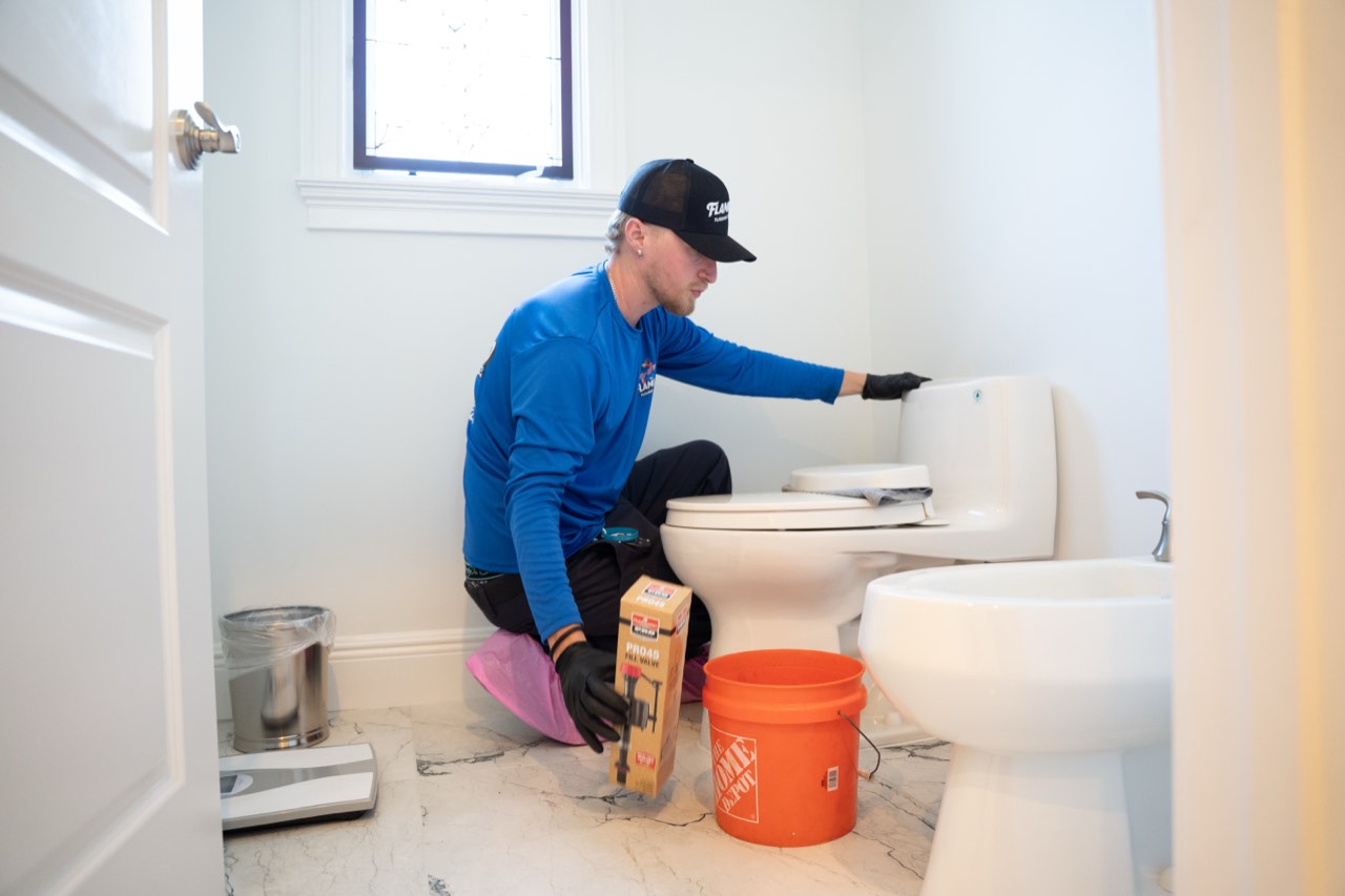 Flamingo technician repairing a toilet fill valve in a customer bathroom
