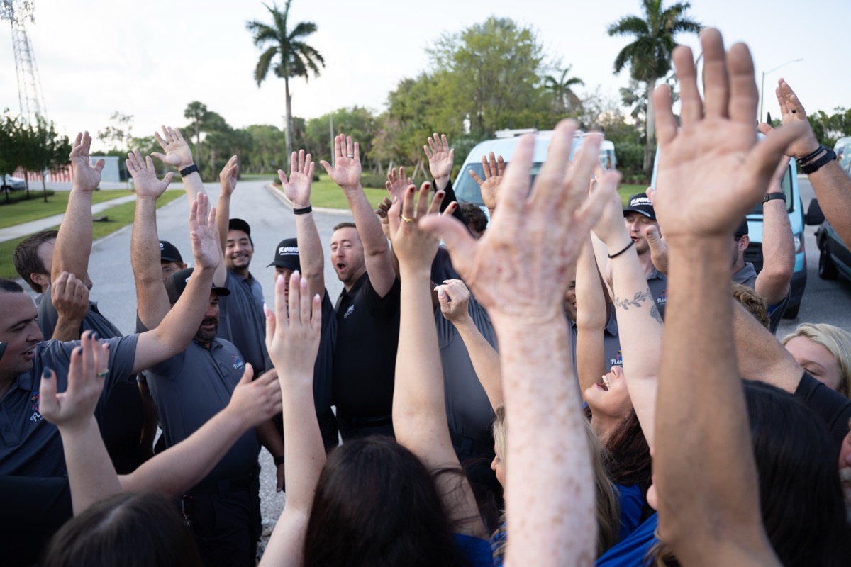 The Flamingo team celebrating together with hands raised